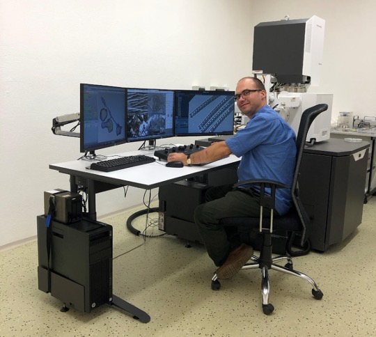 A staff scientist sits at the Thermo Fisher Scientific Volumescope, looking closely at data